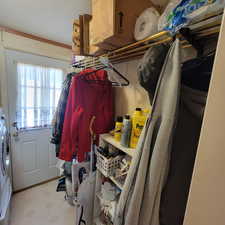 Walk in closet with light floors and washer / dryer