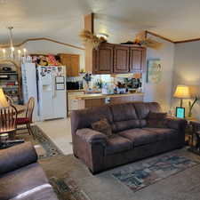 Living room featuring a chandelier, crown molding, lofted ceiling, and a textured ceiling