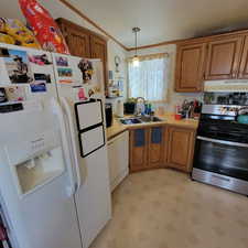 Kitchen with white appliances, light countertops, pendant lighting, light flooring, and brown cabinets