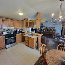 Kitchen featuring a peninsula, light countertops, stainless steel gas stove, lofted ceiling, and decorative light fixtures