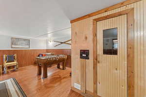 Playroom with wooden walls, a textured ceiling, wood finished floors, and wainscoting