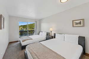 Bedroom featuring access to outside, dark carpet, and a textured ceiling