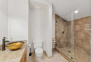 Full bath featuring vanity, walk in shower, light tile patterned flooring, recessed lighting, and lofted ceiling