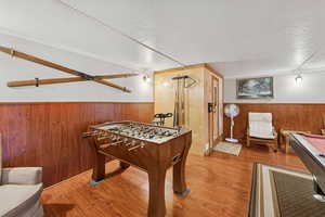 Playroom featuring a wainscoted wall, wooden walls, a textured ceiling, wood finished floors, and billiards