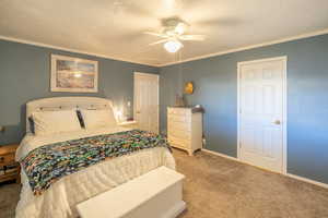 Bedroom with carpet, crown molding, a textured ceiling, and a ceiling fan
