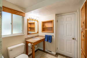 Bathroom featuring healthy amount of natural light, light tile patterned floors, and a textured ceiling