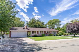 Ranch-style home with concrete driveway, brick siding, an attached garage, and a chimney