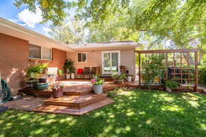 Back of house with a yard, a deck, and brick siding
