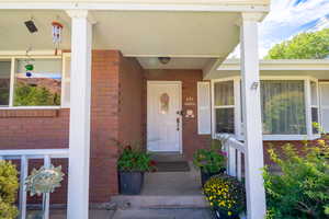 Entrance to property with covered porch and brick siding