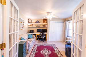 Carpeted office space with french doors and ceiling fan