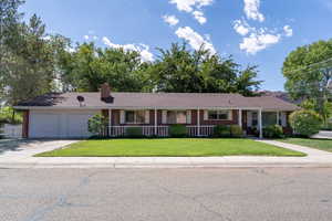 Ranch-style home featuring covered porch, a front lawn, brick siding, concrete driveway, and an attached garage