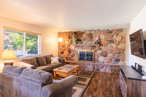 Living area featuring a stone fireplace and dark wood-style flooring