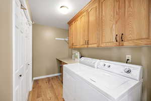 Washroom with light wood finished floors, cabinet space, and independent washer and dryer