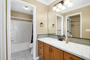 Bathroom with vanity, light tile patterned floors, bathtub / shower combination, backsplash, and crown molding