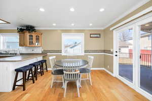 Dining room with crown molding, recessed lighting, healthy amount of natural light, and light wood-style flooring