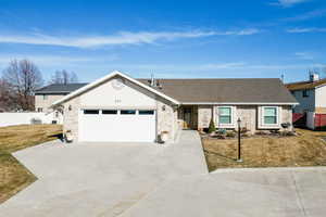 Ranch-style house featuring concrete driveway, a garage, roof with shingles, and brick siding
