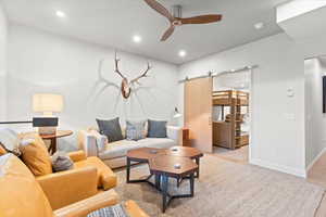 Living area with a barn door, recessed lighting, and ceiling fan