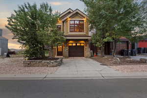 Craftsman-style house featuring concrete driveway, stone siding, and an attached garage