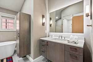 Full bath featuring vanity, a soaking tub, and light tile patterned floors