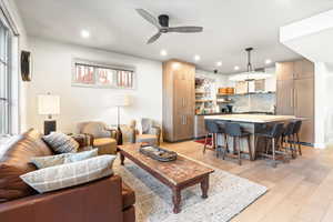 Living area with light wood-type flooring, a ceiling fan, and recessed lighting