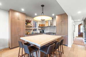 Kitchen with a kitchen breakfast bar, modern cabinets, hanging light fixtures, open shelves, and recessed lighting