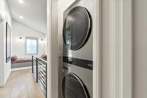 Laundry area featuring light wood-type flooring, estacked washer and dryer, and recessed lighting