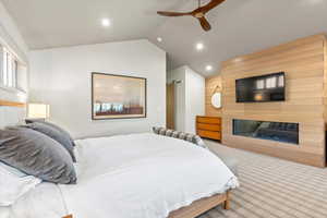 Bedroom with lofted ceiling, carpet floors, ceiling fan, a fireplace, and recessed lighting