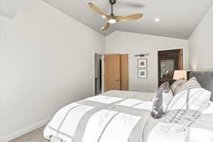 Bedroom with vaulted ceiling, a ceiling fan, and light colored carpet