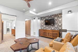 Living room with a barn door, wood finished floors, recessed lighting, ceiling fan, and wallpapered walls