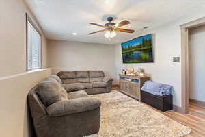 Living room featuring wood finished floors, a textured ceiling, ceiling fan, and recessed lighting