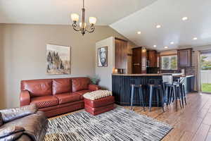 Living room featuring light wood-style flooring, lofted ceiling, recessed lighting, and a chandelier