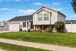 Split level home featuring brick siding, a garage, and concrete driveway