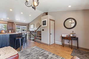Living room with a chandelier, lofted ceiling, recessed lighting, light wood-style floors, and stairs