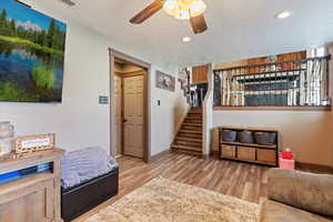 Living area with a textured ceiling, light wood-type flooring, a ceiling fan, stairs, and recessed lighting