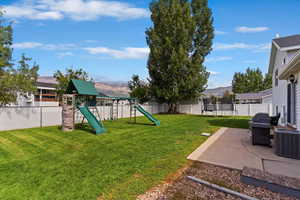 Fenced backyard with a playground, a patio area, a trampoline, and a mountain view