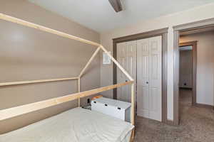 Carpeted bedroom with a closet and ceiling fan