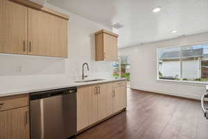 Kitchen featuring dishwasher, light brown cabinets, dark wood-style floors, light stone countertops, and a textured ceiling