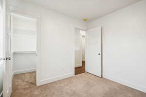 Unfurnished bedroom featuring light carpet and a spacious closet