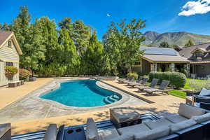 Outdoor pool featuring a patio area, a hot tub, and a mountain view