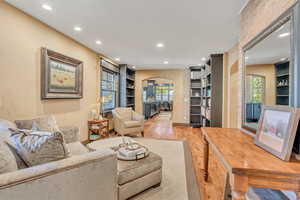 Living area with built in shelves, arched walkways, recessed lighting, and light wood finished floors