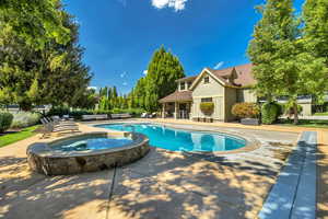 View of swimming pool featuring a patio and an in-ground hot tub