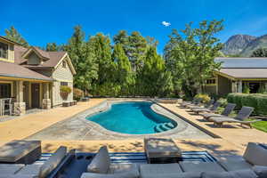 Swimming pool featuring a patio, a mountain view, and a hot tub and pool house
