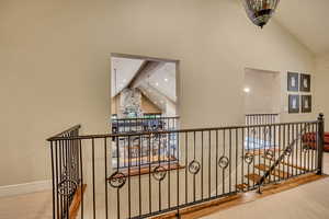 Hallway with beamed ceiling, high vaulted ceiling, and an upstairs landing