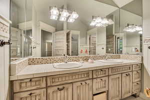 2nd floor Full bath featuring double vanity, backsplash, and lofted ceiling