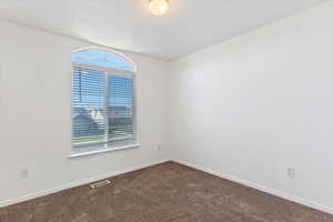 Spare room featuring baseboards and dark carpet