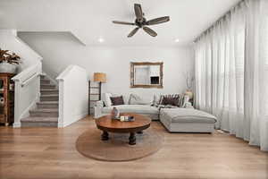 Living room featuring light wood-type flooring, stairway, a ceiling fan, and recessed lighting