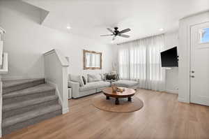 Living area featuring stairway, light wood-type flooring, a ceiling fan, a textured ceiling, and recessed lighting