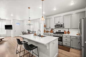 Kitchen featuring gray cabinetry, stainless steel appliances, decorative backsplash, a kitchen bar, and recessed lighting