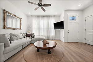 Living room with light wood finished floors, ceiling fan, and recessed lighting