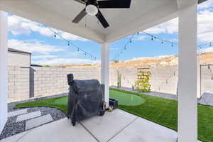 Fenced backyard with a putting area, a patio area, a grill, and ceiling fan